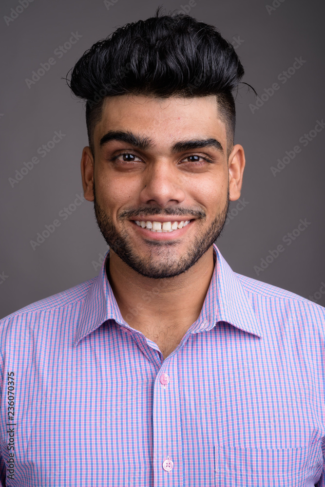 Young handsome Indian businessman against gray background Young handsome Indian businessman against gray background