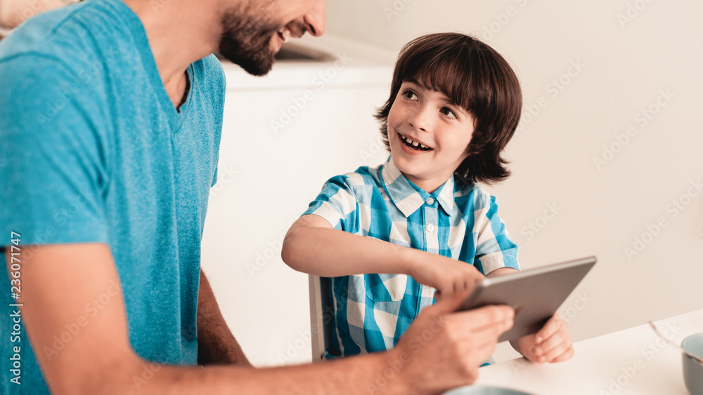 Obraz premium Happy Young Father and Son Using Tablet at Home.