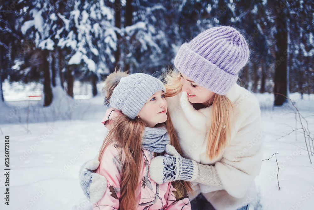 Mother and child girl having fun, playing and laughing on snowy winter walk in nature.