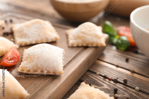 Board with uncooked ravioli on wooden table
