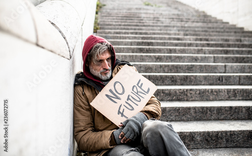 Obraz na płótnie Homeless beggar man sitting outdoors in city holding no future cardboard sign