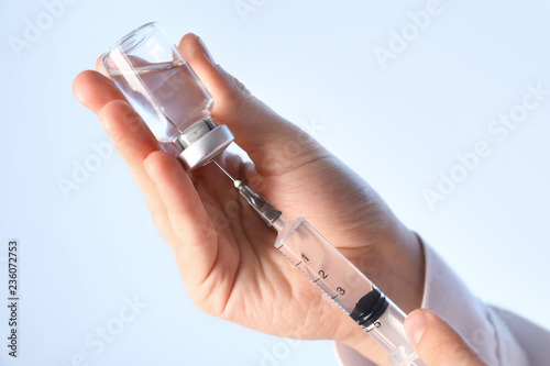 Doctor preparing syringe for injection on light background, closeup photo