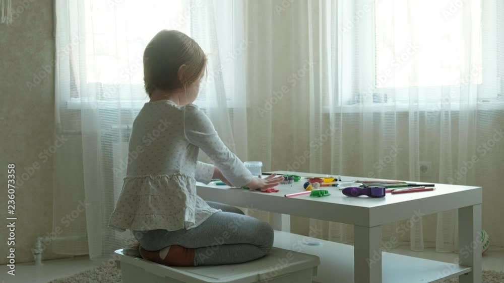 a little girl plays with plasticine, rolls it with her hands, there are figures and colorful pencils on the desktop, the development of fine motor skills a little girl plays with plasticine, rolls it with her hands, there are figures and colorful pencils on the desktop, the development of fine motor skills