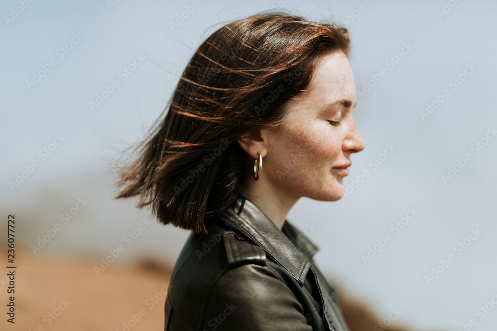 Obraz premium Side view of a woman in leather jacket standing in a park