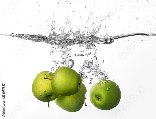 Falling of apples into water on white background