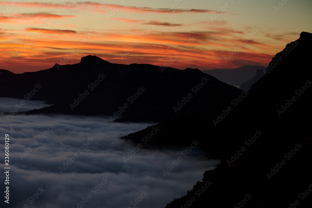 Mountain range with visible silhouettes through the morning colorful mist. Abstract background with mountains