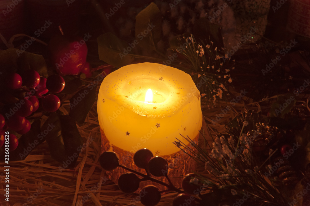 Stockfoto Candella natalizia. Luce soffusa della candela natalizia con  decorazioni ed ornamenti sullo sfondo. Atmosfera di Natale.