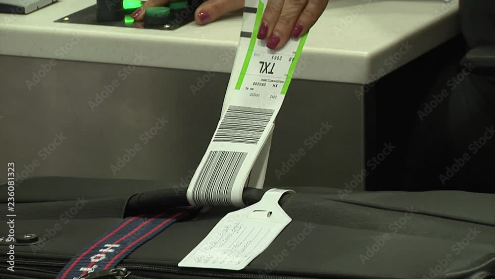 Close-up of an airport worker putting travel tags on luggage at the baggage check in desk