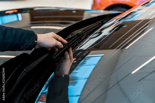 partial view of businessman adjusting windshield wipers of black automobile