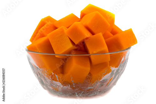 Pieces of raw pumpkin in a glass bowl. Vegetarian food. Raw vegetables. Isolated on white background. Orange flesh of ripe fruit.