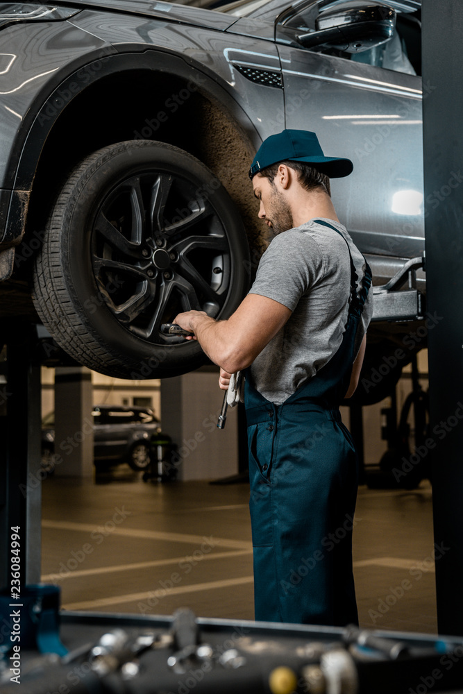 auto mechanic in uniform fixing car wheel at auto repair shop