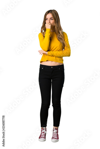 A full-length shot of a young girl with yellow sweater having doubts on isolated white background