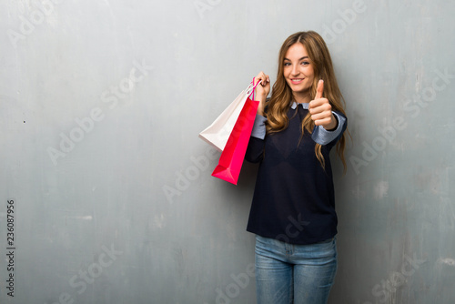 Girl with shopping bags giving a thumbs up gesture because something good has happened