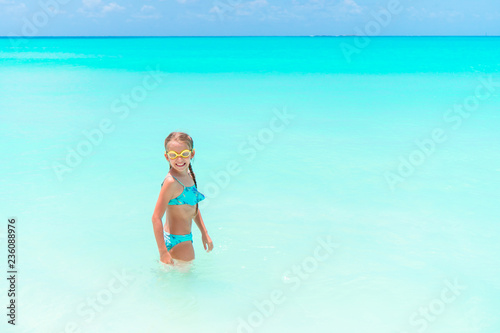 Little happy girl splashing and having fun in the shallow water. Kid in swimsuit playing with sand