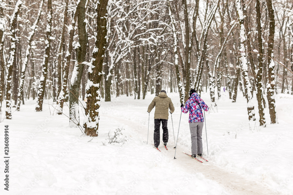 Couple of people enjoying cross-country skiing in city park or forest in winter. Family Sport outdoor activities in winter season concept. Healthy lifestyle