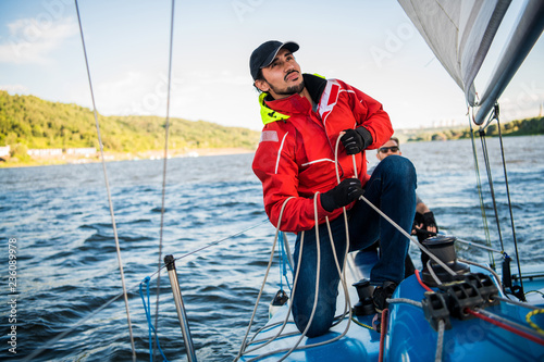 Young man working on sailing ship, active lifestyle, summer sport concept