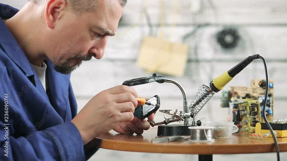 the engineer is engaged in repair of the old mobile phone the engineer is engaged in repair of the old mobile phone