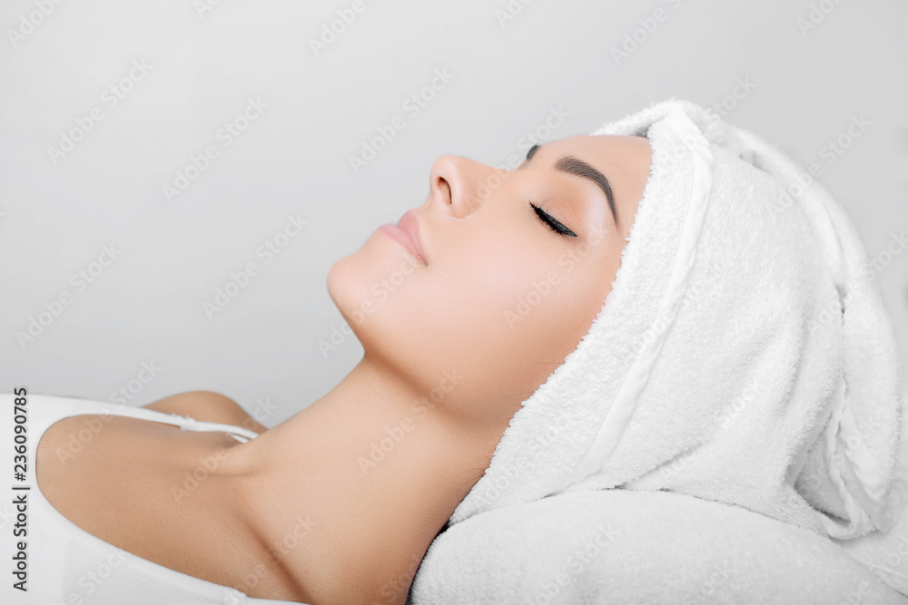 woman with clean fresh face, with towel on head, relaxing after spa receiving treatment. Women with perfect skin enjoying a skin care treatment