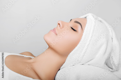woman with clean fresh face, with towel on head, relaxing after spa receiving treatment. Women with perfect skin enjoying a skin care treatment