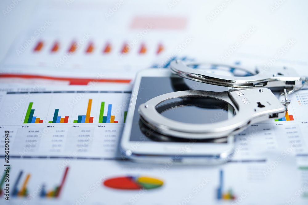 Fototapeta premium Metal handcuffs and mobile phone on chart graph background. Hacker economy finance banking static concept.