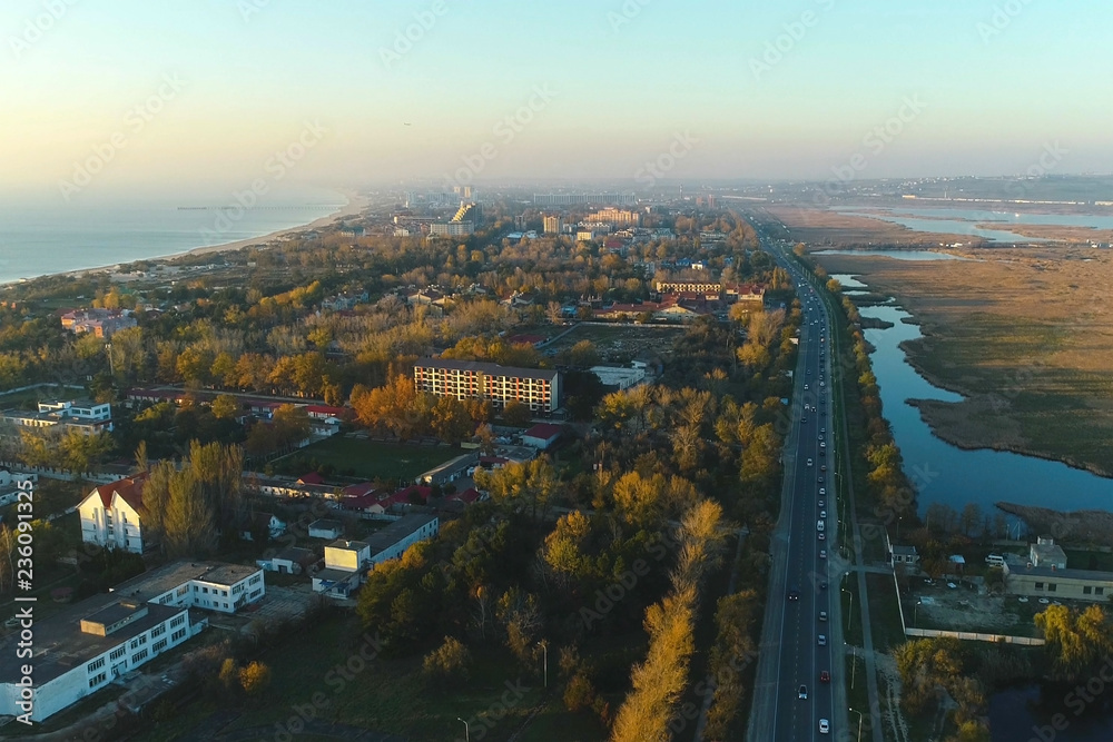 Beautiful evening view of coastal city with roadway and wet meadows. Aerial photo.