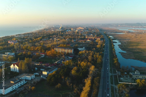 Beautiful evening view of coastal city with roadway and wet meadows. Aerial photo.