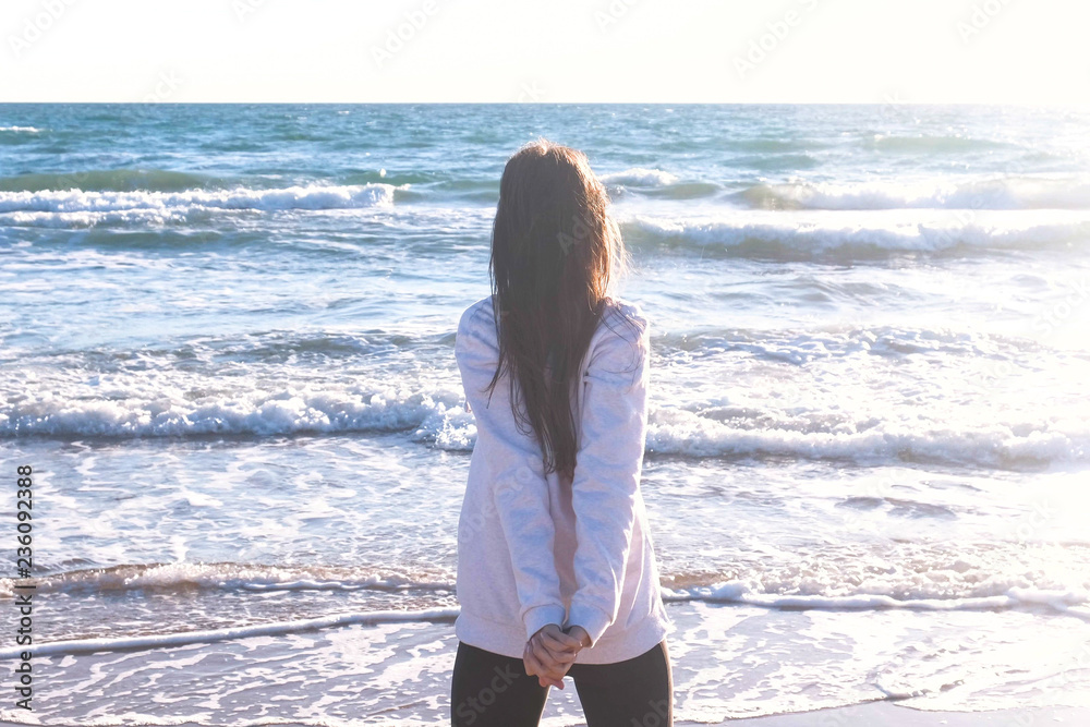 Woman is stretching doing yoga on the sand beach with waves, back view. Woman is stretching doing yoga on the sand beach with waves, back view.