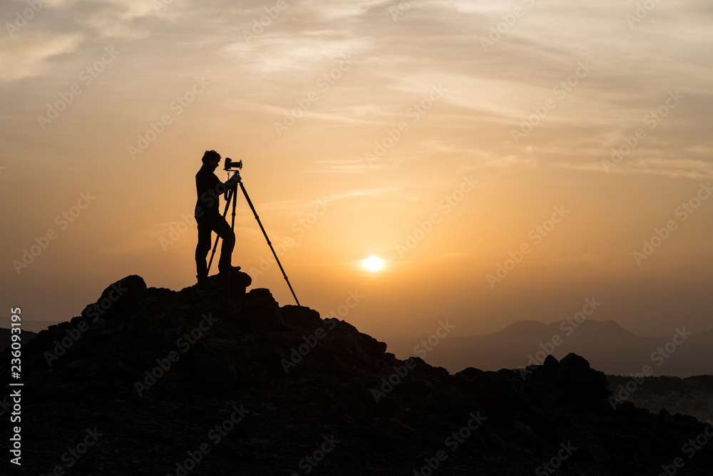 Silhouette of male landscape photographer shooting with a tripod