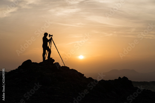 Silhouette of male landscape photographer shooting with a tripod