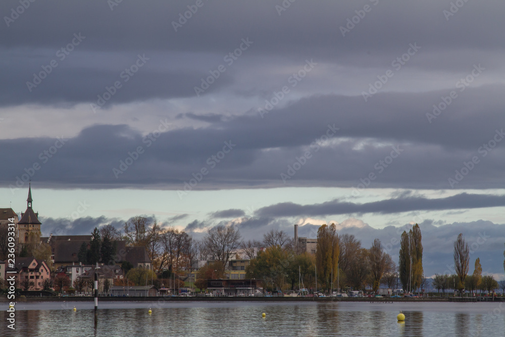 Fototapeta premium Dunkle Wolken über dem Bodensee mit Stadtansicht