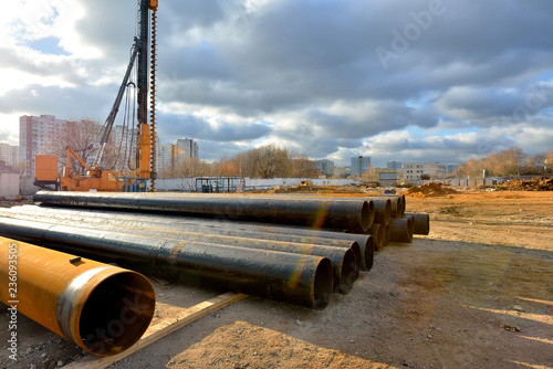 Pile driving machine and metal pipes on a construction site