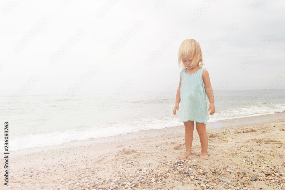 Little girl dressed in blue shirts is walking on the beach. Little girl dressed in blue shirts is walking on the beach.