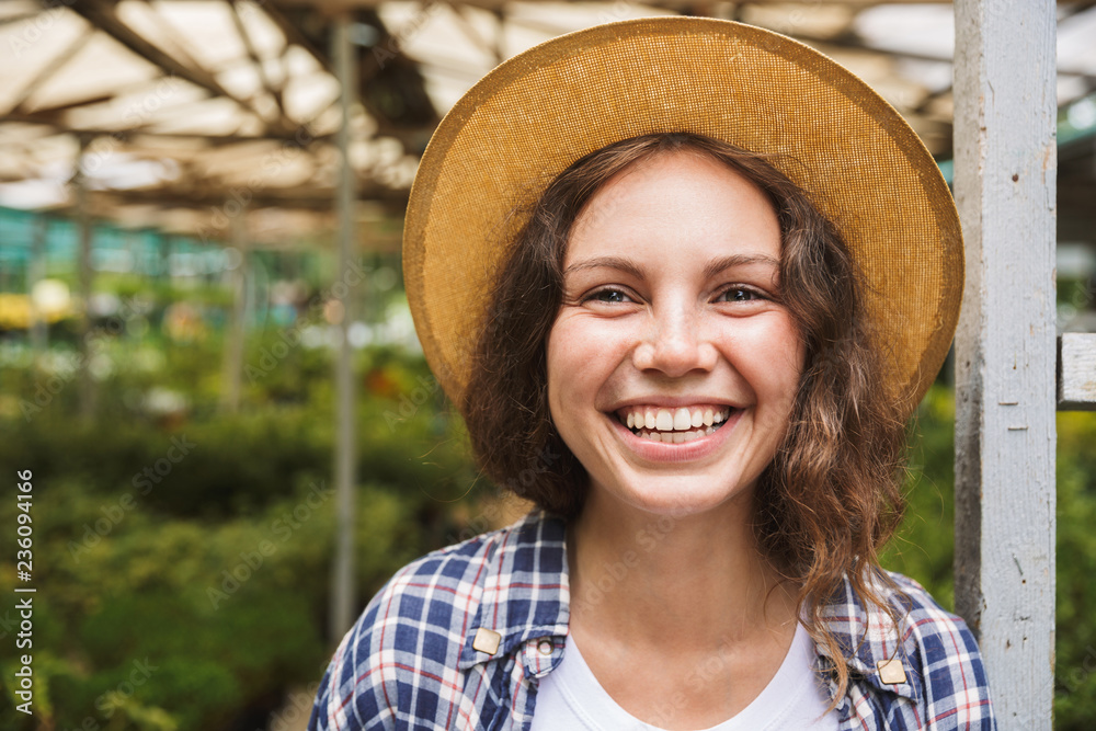 Cheerful young woman standing at a greenhouse