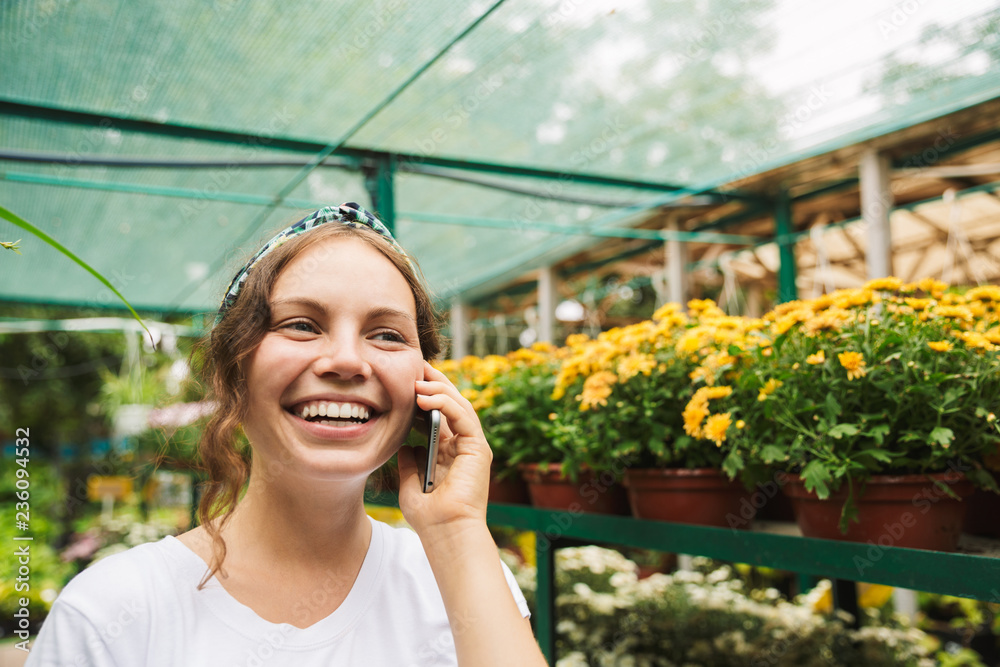 Fototapeta premium Cheerful young woman gardener talking on mobile phone