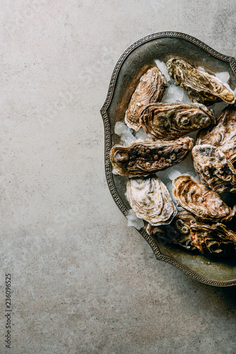 flat lay with oysters in metal bowl with ice on grey surface