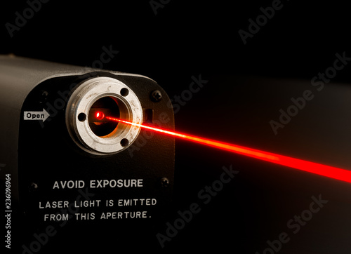 Laser beam from lab laser. Warning notice on front. Aperture is not noisy, it looks this way due to diffraction of coherent light at aperture boundary. Beam made visible by mist sprayed into air.