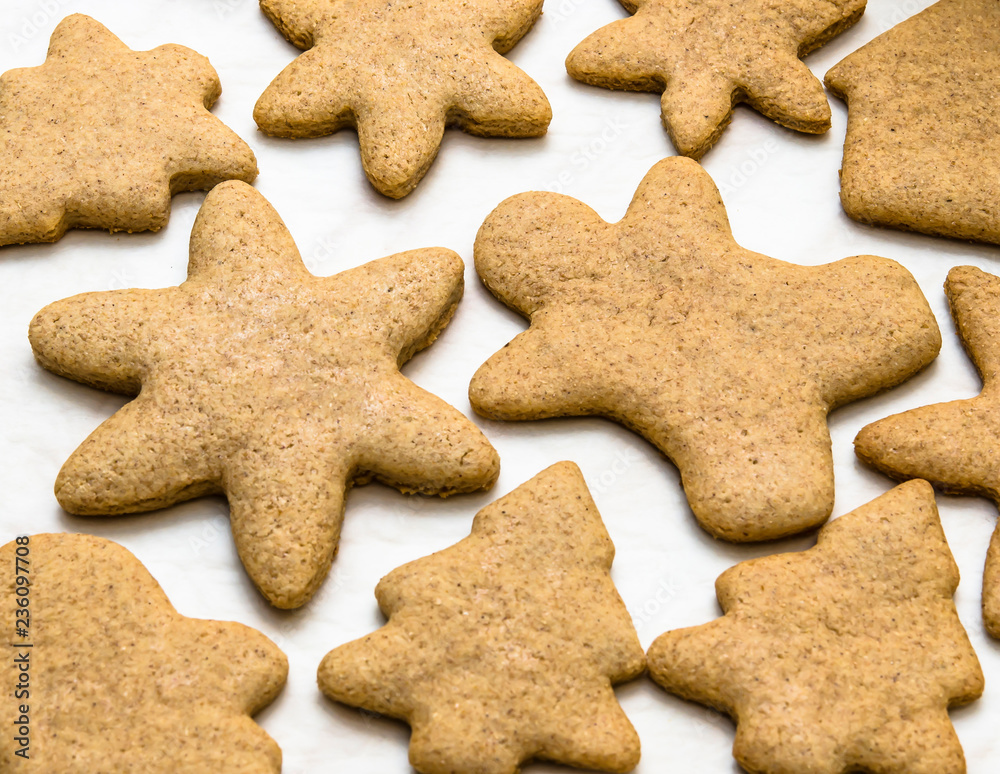Home-baked gingerbread on a kitchen surface with baking paper - Christmas concept with home-baked cookies in the kitchen Home-baked gingerbread on a kitchen surface with baking paper - Christmas concept with home-baked cookies in the kitchen
