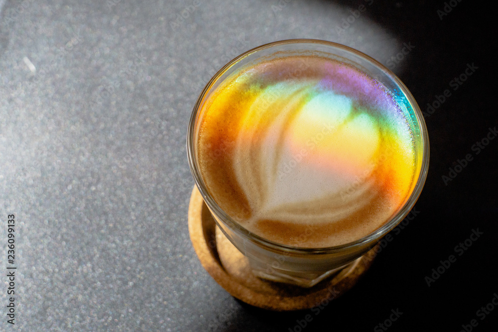 A prism dispersing sunlight splitting into a spectrum on coffee cup with heart shape latte art foam on black table,LGBT flag effect. A prism dispersing sunlight splitting into a spectrum on coffee cup with heart shape latte art foam on black table,LGBT flag effect.