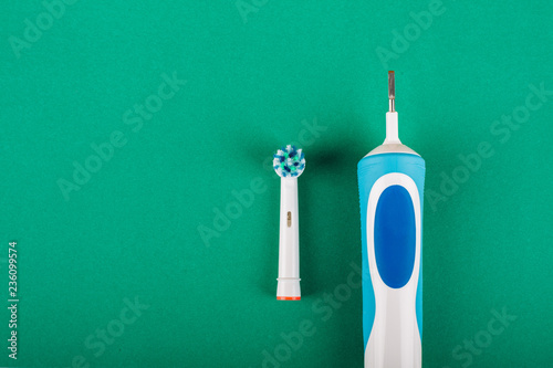Electric toothbrush on a green background. Tips for a toothbrush. Copy space.