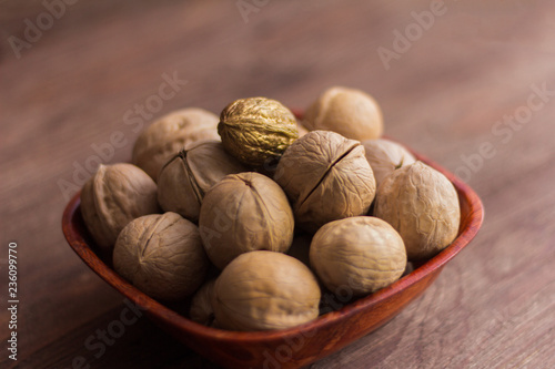 full bowl of walnuts on wooden background