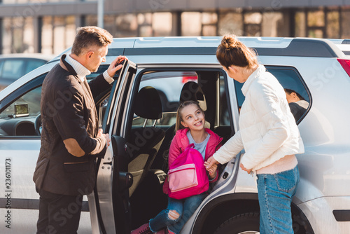  Preteen daughter sitting in car with opened door near perents photo