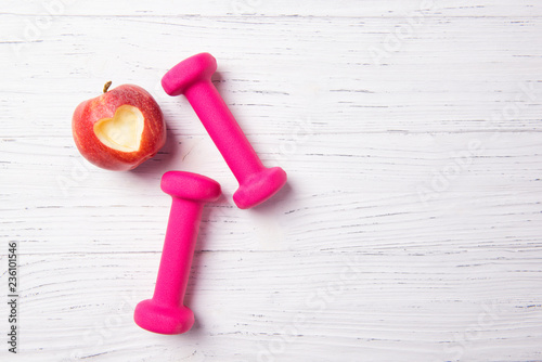 Pink dumbbells and apple with heart, fitness concept, healthy lifestyle, top view