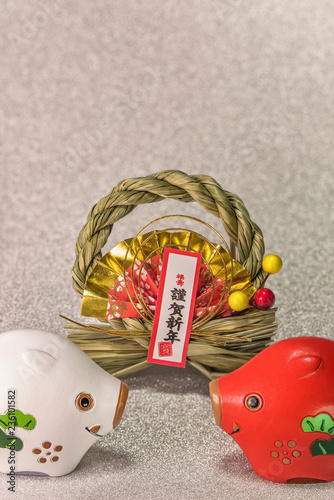 Japanese New Year's Cards with black handwriting ideograms Gingashinnen which means Happy New Year with cute Zodiac animals figurines of two boars on silver background.  photo