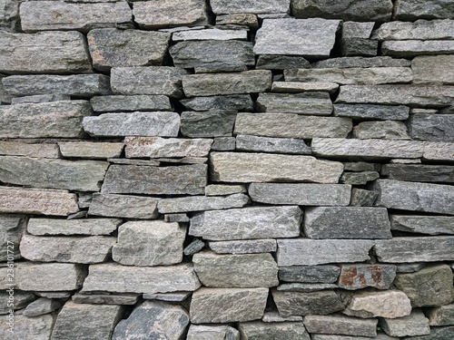 Decorative exterior stone wall from irregural natural grey stones as background