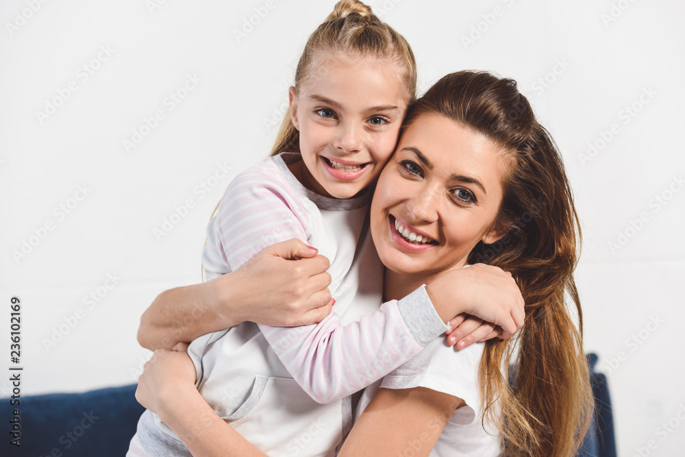 Mom and daughter embracing and smiling at home Mom and daughter embracing and smiling at home