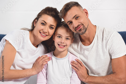 happy smiling parents hugging daughter in pajamas