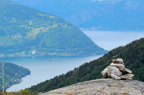 Stone cairn in Husedalen valley with cascade of four waterfalls, Kinsarvik, Norway photo