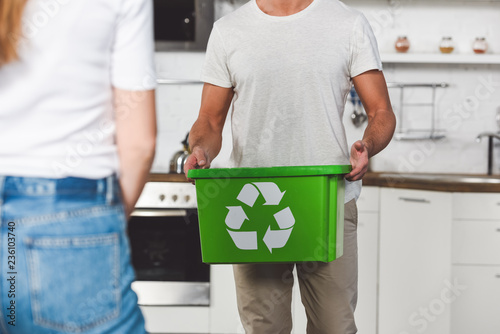 cropped with of man standing with green recycle box at kitchen