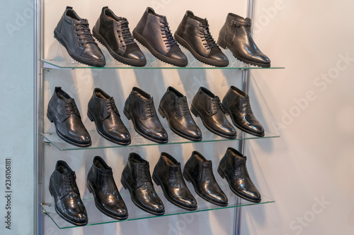 Men's leather shoes on the shelf in the store. Racks in the store of clothes and accessories. Shelves with stylish men's shoes. Many classic shoes and boots.