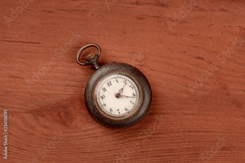 A vintage pocket watch, shot from the top on a dark rustic wooden background with a place for text